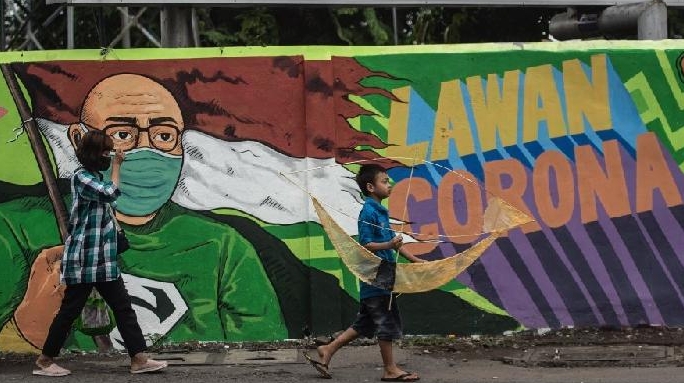 Pedestrians walk past a mural warning residents of COVID-19 along a street in Surabaya. AFP Pedestrians walk past a mural warning residents of COVID-19 along a street in Surabaya. AFP