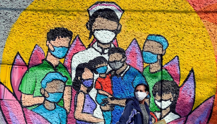 A woman walks past a mural painted by students and professors from the Faculty of Arts and Design of National Autonomous University of Mexico (UNAM) to honor health workers fighting the coronavirus on the walls of the National School of Nursing and Obstetrics in Mexico City. AFP