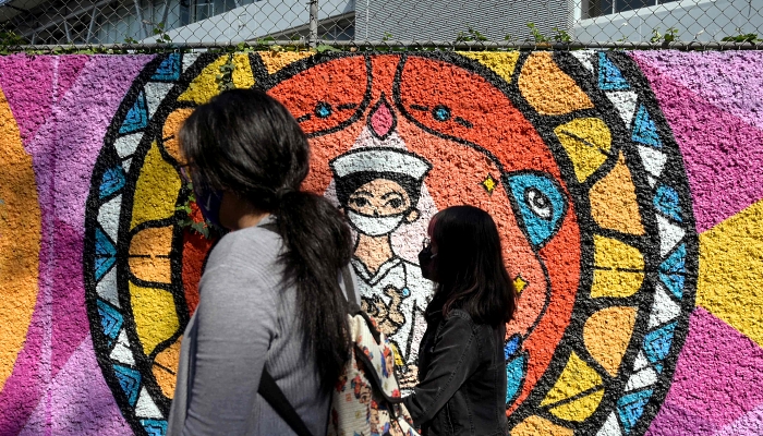 People walk past a mural painted by students and professors from the Faculty of Arts and Design of National Autonomous University of Mexico (UNAM) to honor health workers fighting the coronavirus on the walls of the National School of Nursing and Obstetrics in Mexico City. AFP