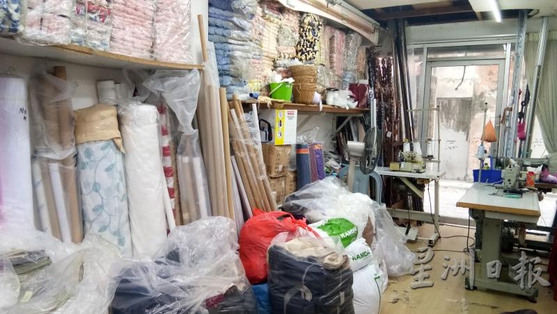 福昇布庄店有一名”御用“裁缝师，在店内一处角落帮助顾客缝制窗帘布。