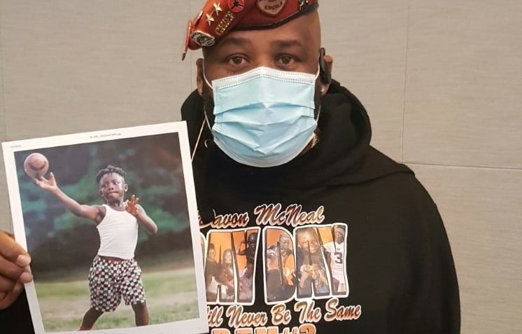 John Ayala holds up a picture of his grandson Davon McLean, who was killed by a stray bullet in southeast Washington, DC. AFP