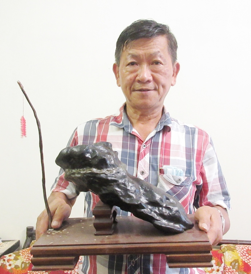 卜福辉拿著“醒狮”形状的雅石；这雅石曾经夺得全国特优奖，也曾经拿去北京参加国际赛。