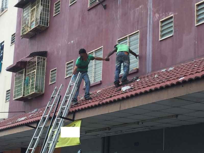 在缺乏安全帽、安全绳等安全设备之下，组装人员站在屋顶上准备安装广告牌，暴露在风险当中。