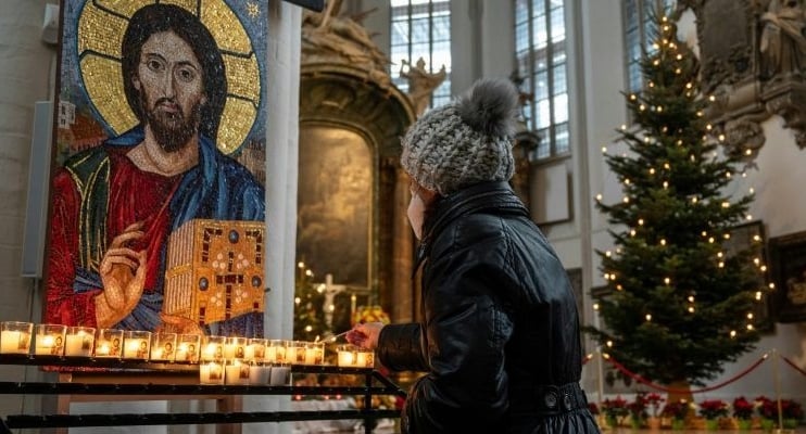 In Berlin, a worshipper lights a candle at St Mary's church ahead of an outdoor mass on Christmas Eve. AFP