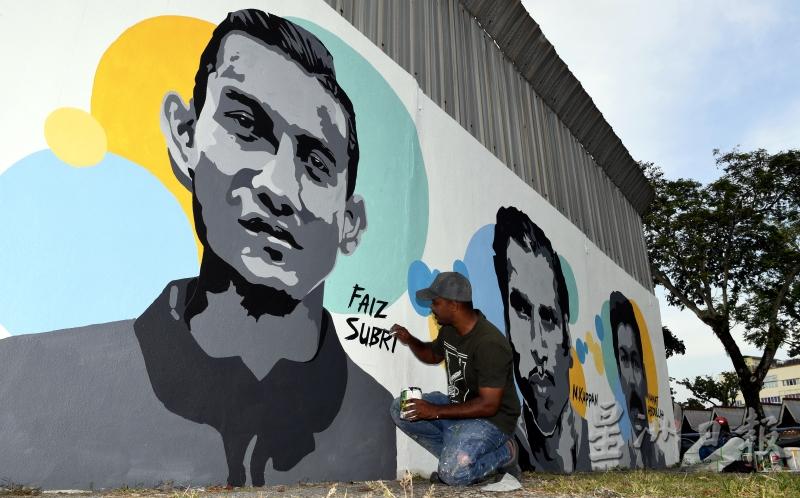 莫哈末阿兹米全神贯注在体育馆外墙绘画，以赶在元旦日完成壁画工程。