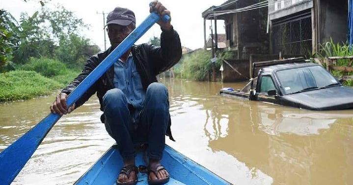 A man rows a boat along a flooded street caused by heavy rain in Bandung, Indonesia. AFP