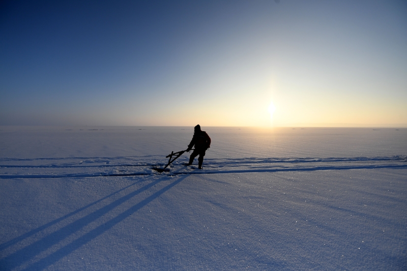 渔民在乌伦古湖凿开的冰眼进行冰下水线传递。（图：新华社）

