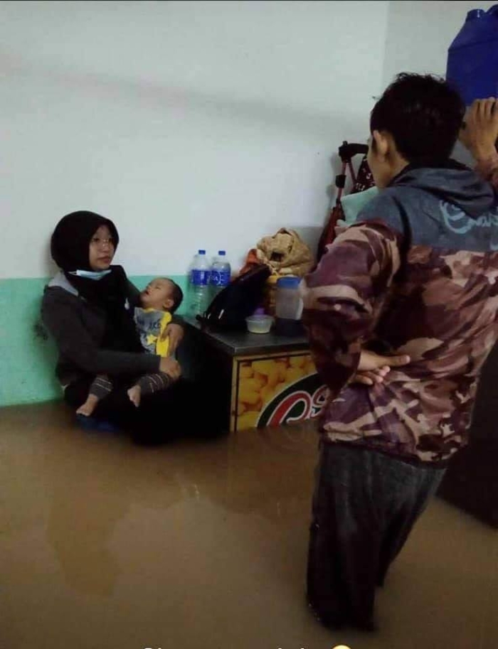 水淹入屋，叶淘沙平民屋住民抱著孩子等待迁入疏散中心。（图片取自网路）
