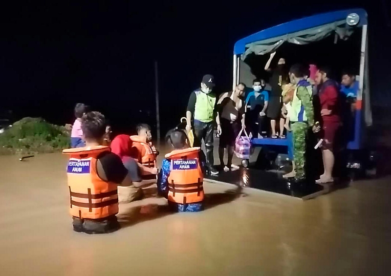 民防部队、警方及志愿警卫成员合作下，周日漏夜将新山陈厝港的灾民迁移到武吉珍珠国小疏散中心。（马新社图）