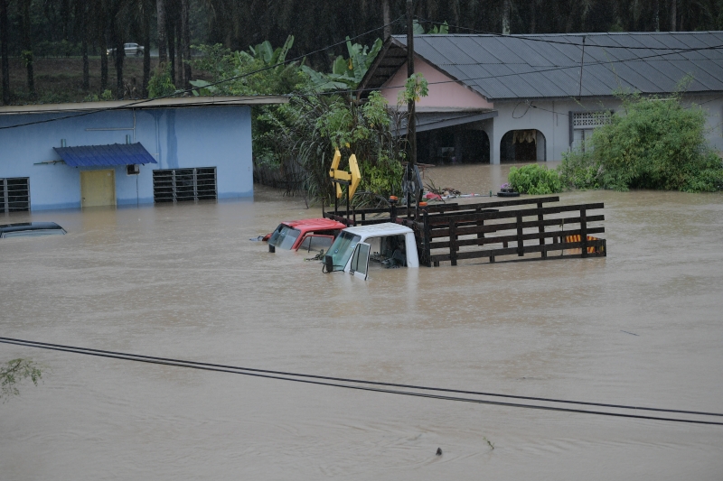 在新山甘榜士峇卡峇鲁，两辆罗里几乎被洪水淹没（马新社图）
