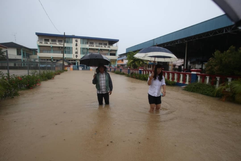 哥打丁宜市区的培华华小整个校园被浸泡在水中，董事长黎华财（左）与校长黄赛珠（右）到学校视察灾情。