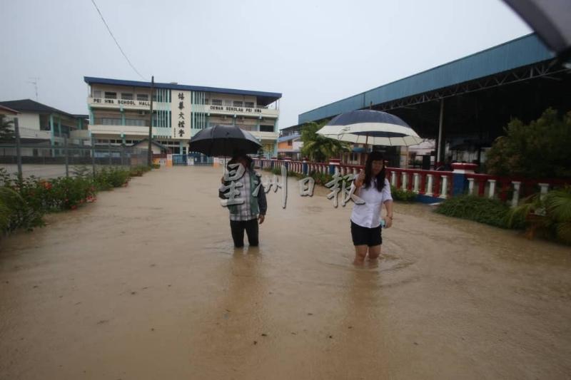 哥打丁宜市区的培华华小整个校园于今早被浸泡在水中，董事长黎华财（左）与校长黄赛珠（右）到学校视察灾情。