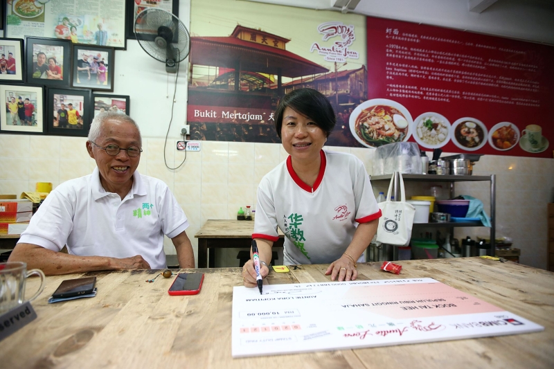 杨亚花（右）在模拟支票上签名，以示“一碗一元结一缘”筹款活动圆满结束。