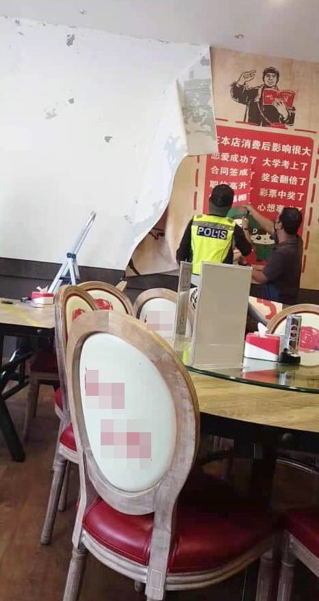 警员到餐馆撤下壁纸。（照片取自脸书）
