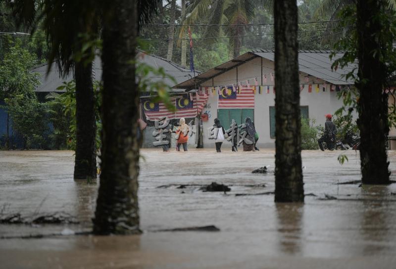 新山的甘榜士峇卡峇鲁被洪水淹及后，灾民只能涉水而过。