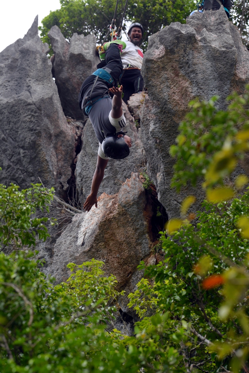 登山爱好者系上安全带和保护绳倒挂著身体往下滑落。