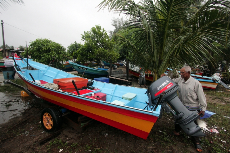 莫哈末雅兴因狂风大浪无法出海，只好定时检查停靠在陆地上的渔船引擎。（马新社照片）