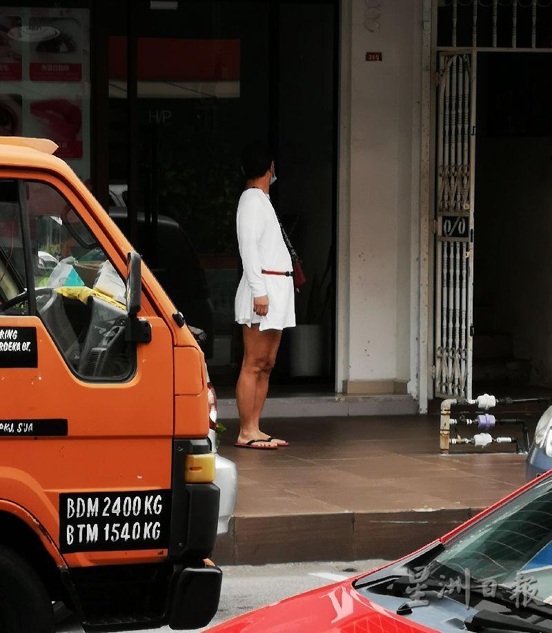 一套女性连身白色短裙的男子出现在马六甲拉也，不是在店铺前的玻璃门照镜子，引起附近民众注意。
