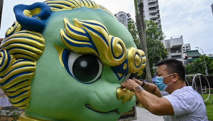 A worker gives the finishing touch to a guardian lion statue in front of Sun Yat Sen Nanyang Memorial Hall in Singapore ahead of the Lunar New Year. AFP