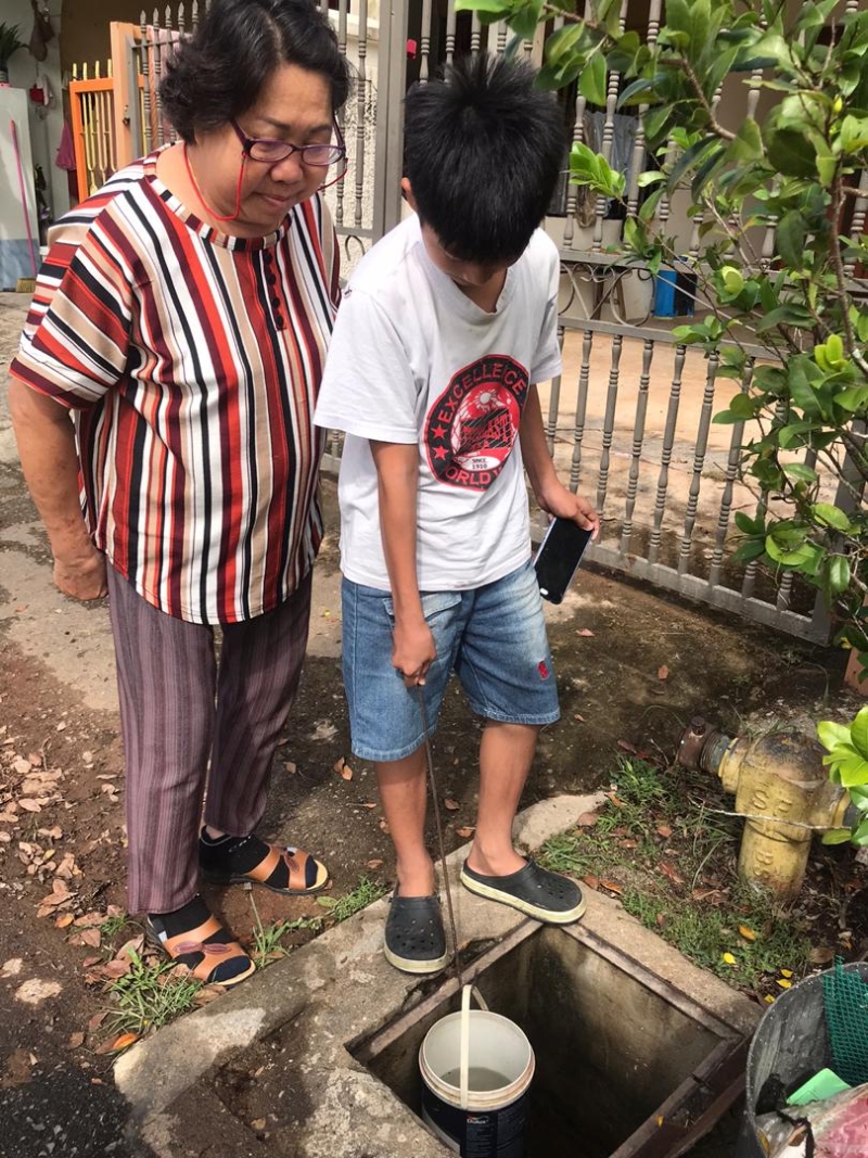 积罗新村星星花园居民罗秀珍和孙子提着水桶到附近消防栓水龙头装地下水。