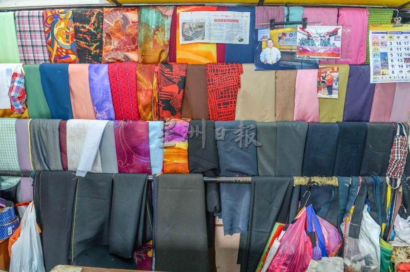 陈铭的裁缝店工作空间不大，里面可见到各色布匹，整齐排列。