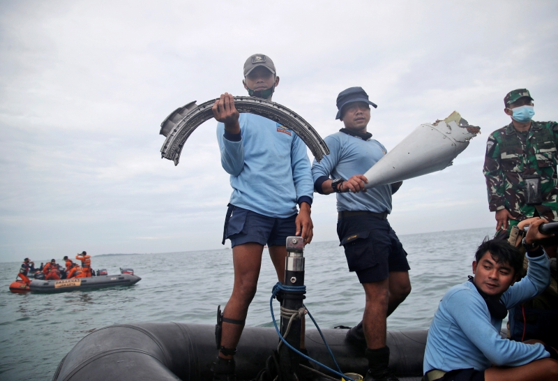 海军潜水部队人员展示刚打捞的客机残骸。（美联社照片）