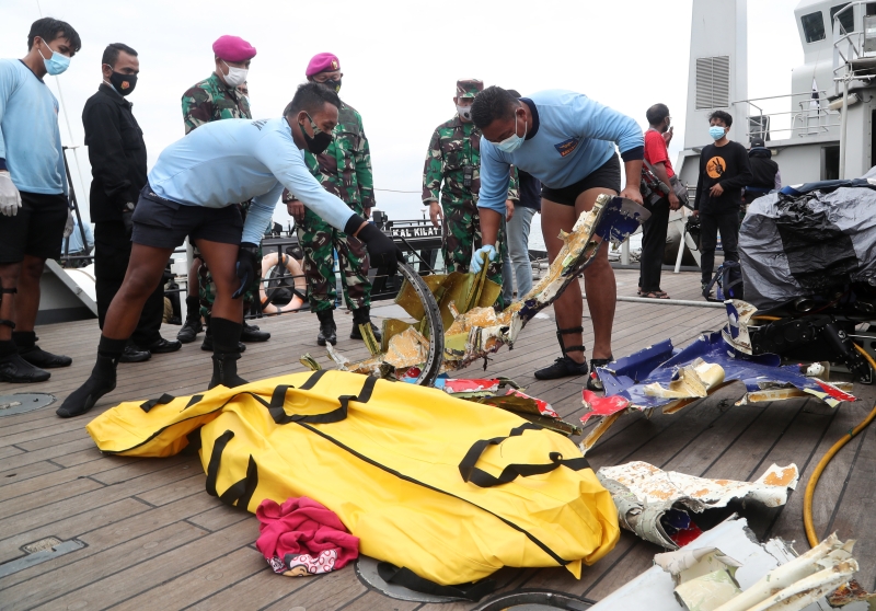 潜水人员将打捞起客机残骸堆放一起，供当局检查鉴定。（欧新社照片）