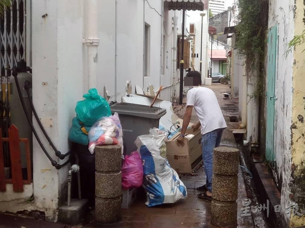 民众将一箱垃圾直接放在垃圾桶旁，而不是丢入垃圾桶内。