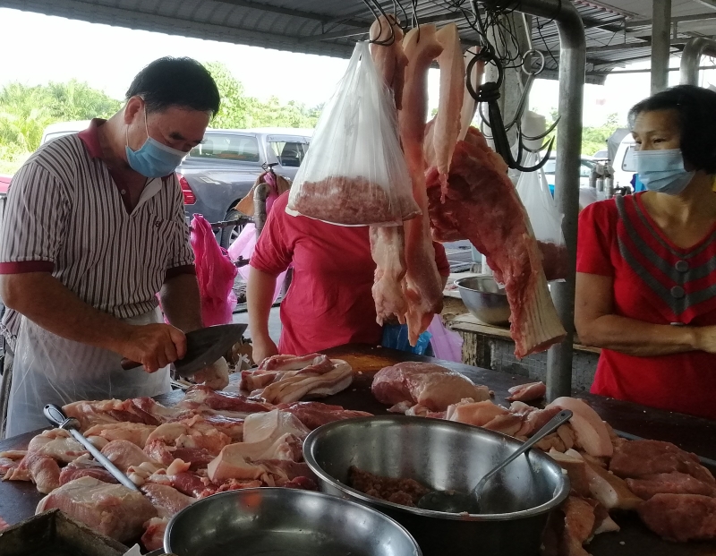 黄汉德（左）表示，这两日购买猪肉的顾客确实增多，但大家都是适量而买。