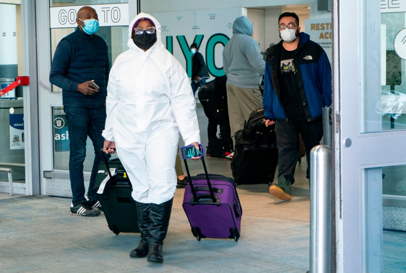 美国疾病控制与预防中心（CDC）周二下达新规，由本月26日起，所有来美的国际航班旅客，都要提供出发前72小时内的无染疫证明。图为一名全身防护的旅客抵达纽约肯尼迪国际机场。（图：法新社）