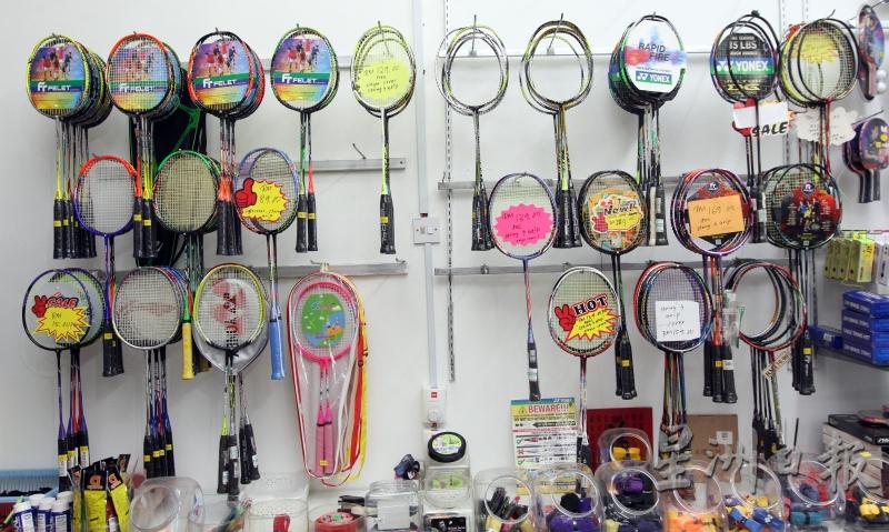 玲琅满目的羽球拍井然有序地张挂在墙壁上，等候顾客挑选。

