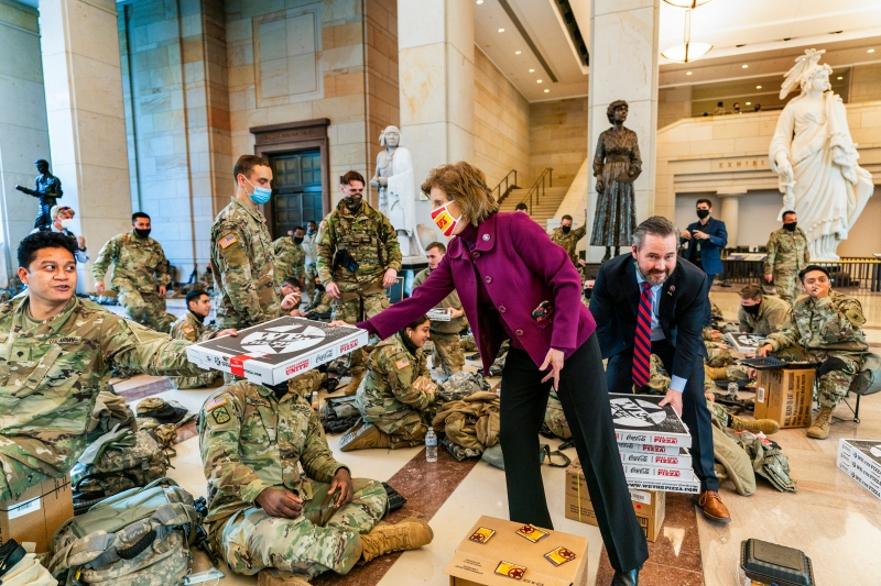 两名共和党籍的众议员周三向提前进驻国会大楼驻守的国民卫队成员派送披萨。（美联社照片）