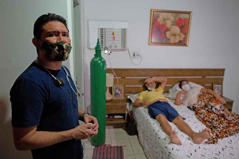 巴西亚马逊州疫情严峻，首府马瑙斯面临医疗体系崩溃、氧气瓶短缺。图为一名急诊室医生被迫在家救治冠病重症的72岁老父和56岁母亲。（法新社照片）