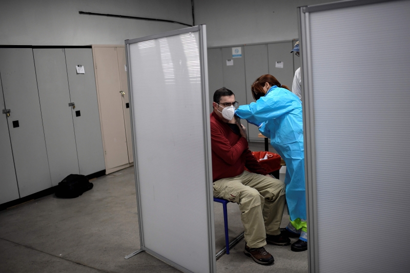 在西班牙首都马德里，一位医护人员正接受疫苗接种.