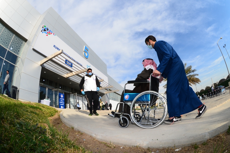 在科威特哈瓦利省的新冠疫苗接种中心，一名老人坐轮椅准备前往接种第二剂疫苗。