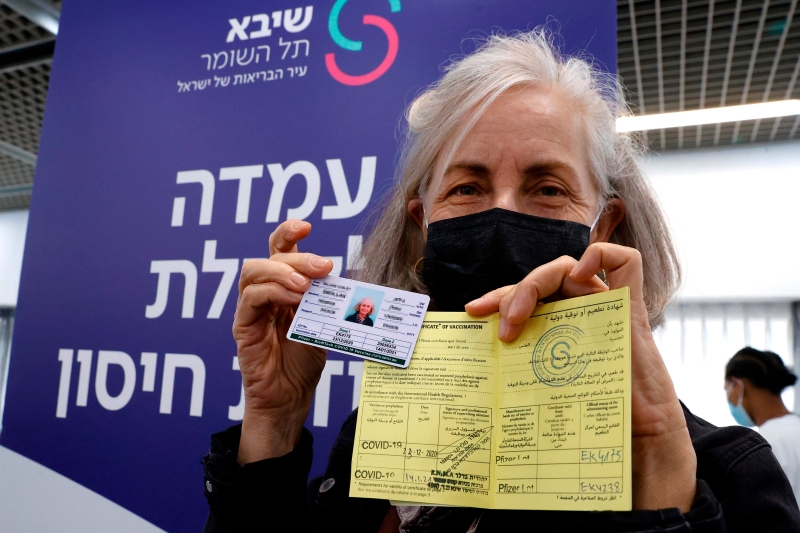 以色列医护人员接种后，向媒体展示她的国际卡和接种疫苗证书。