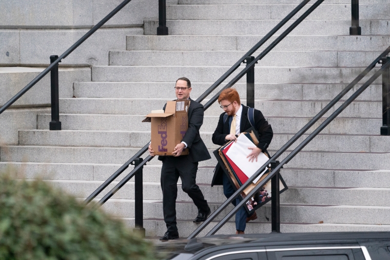 两名男子抬着装有各种用品的箱子，撤离艾森豪威尔行政办公大楼。（图：欧新社）