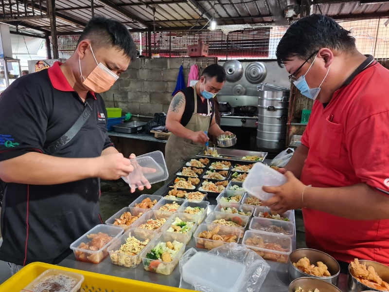 外卖饭食订单倍增，陈振辉（中）与合作伙伴忙于备餐。