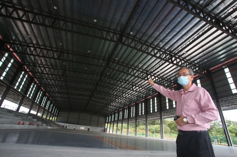 校长江宁福向记者介绍该校的有盖球场建设。