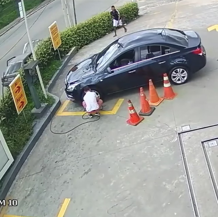 司机蹲在车轮前充气，小偷从另一侧悄悄靠近。