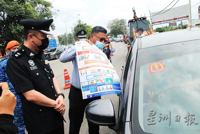 沙罗尼占赠送防疫海报给公路使用者，左为胡昌福。