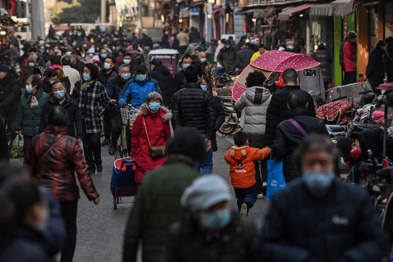 武汉一个市场附近一条街道，采购必需品的民众煕来攘往，大家都努力地遵守新常态的生活形态，戴口罩出门。（法新社照片）
