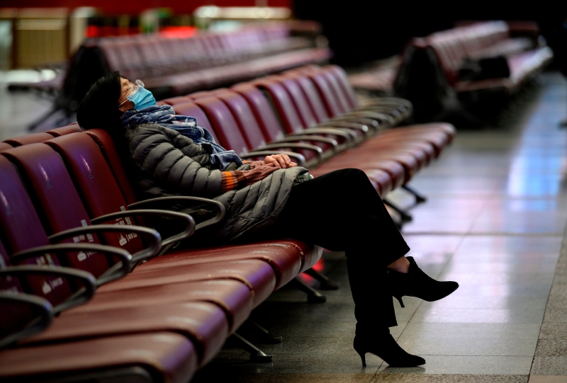 一名准备回家过年的乘客在北京火车站候车厅休息。
