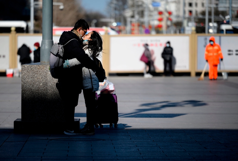 一对情侣在北京火车站外深情拥抱。