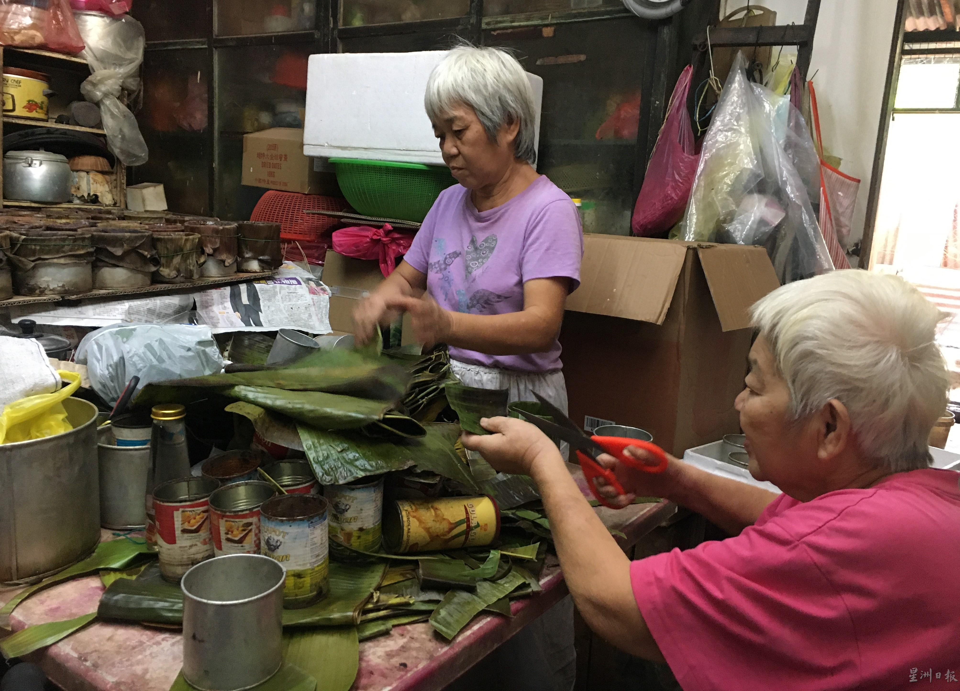 刘秀珍（左）和刘秀群修剪香蕉叶，并垫在容器里，为制作年糕做好准备功夫。
