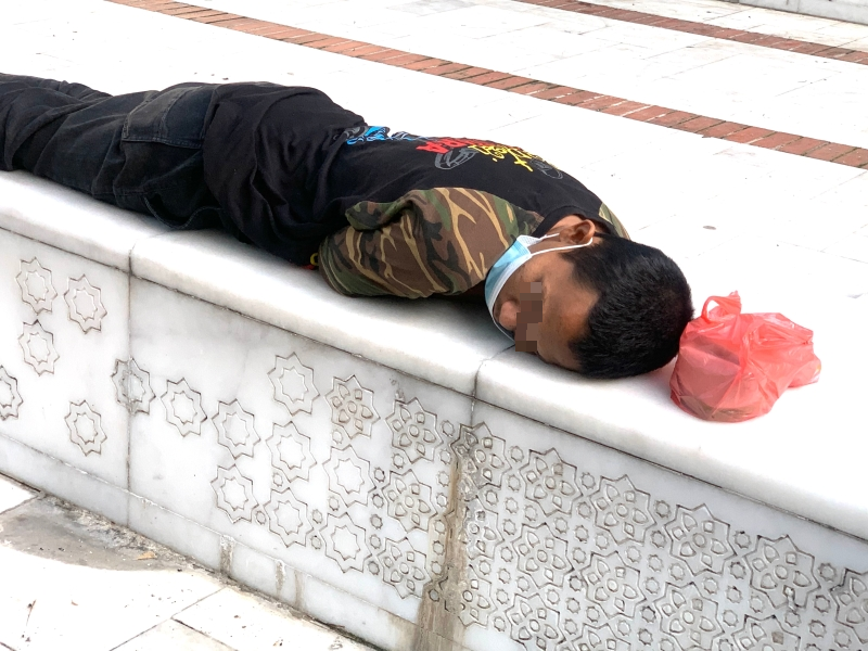 居无定所的街友，躺在石凳上睡觉。