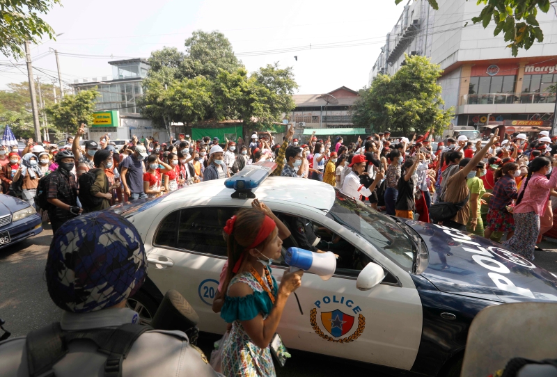 缅甸人民上街示威游行，沿途经过一辆警车。