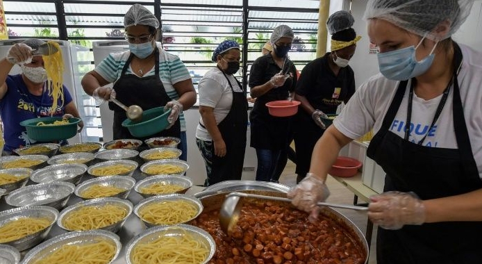 Workers prepare meals at a soup kitchen in Paraisopolis favela, where traditional loans are a nearly impossible dream for households and businesses. AFP