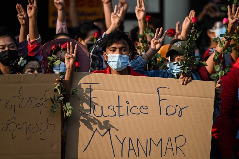 示威群众手持花朵并展示标语，为缅甸争取正义。（法新社照片）