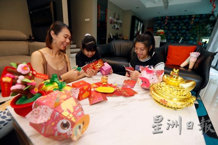 年关将至，陈丽玲（左）与大女儿陈乐易（右）和小女儿陈乐欣利用红包封制作手工装饰，让家里增添浓浓的新年气氛。